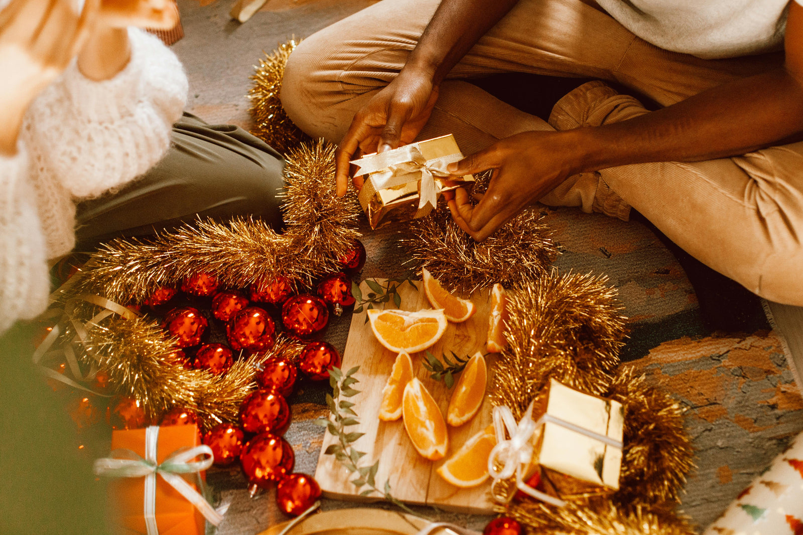 A wooden board of festive fruits surrounded by festive decorations and gifts