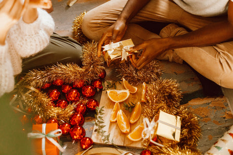 A wooden board of festive fruits surrounded by festive decorations and gifts